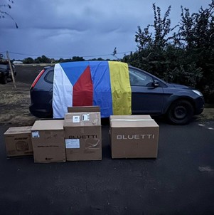 Bluetti powerbanks klaar voor transport naar Oekraïne, met Oekraïense vlag op de auto.